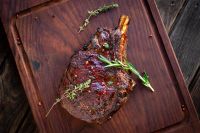 Close-up of Wagyu rib steak showing rich marbling and bone structure on a butcher board.