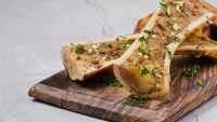 Roasted Wagyu marrow bones with golden crust and fresh herbs on a serving tray.